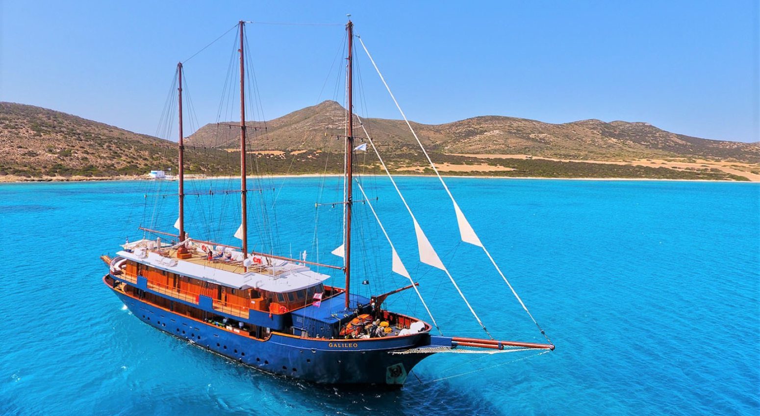 The Galileo sailing in the sea with mountains in the background