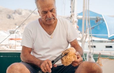A person holding a sea sponge sitting in a boat in Kalymnos island, Greece