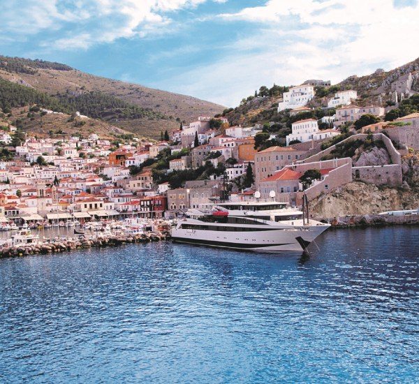 Variety Cruises' Voyager anchored with a tradional port in the background