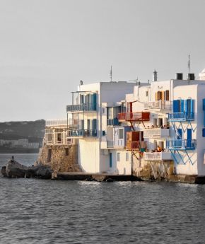 The iconic windmills of Mykonos, Greece, with the colorful town in the background