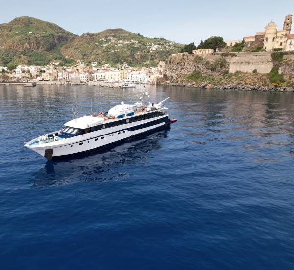 Variety Cruises ship anchored with a traditinal port and town in the background