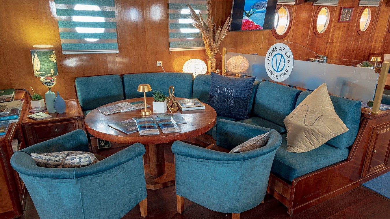 The lounge area of a Variety Cruises ship, with blue armchairs and blue couches