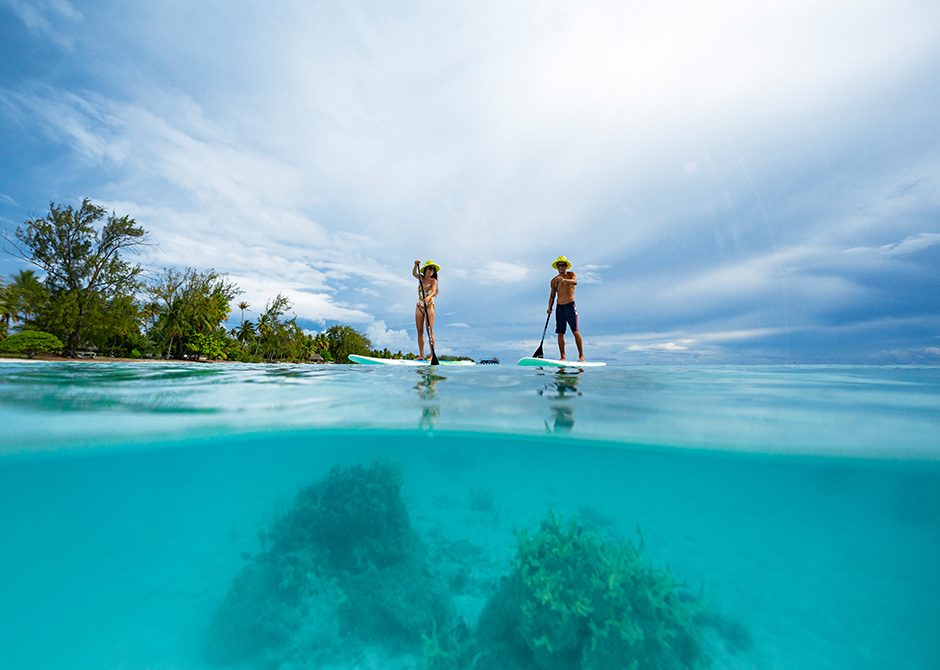 A couple kayaking in turquoise wates with tropical islands in the background