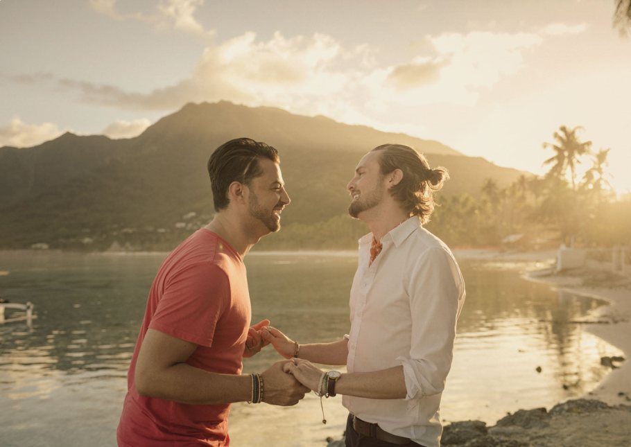 A couple holding hands and laughing with the sunset in the background