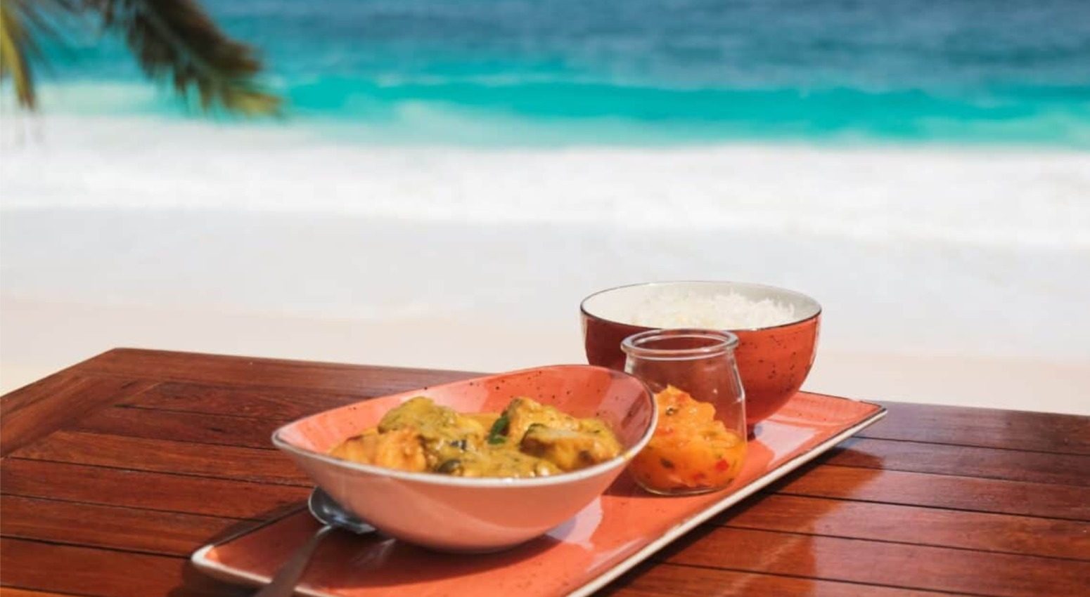 A plate of octopus curry with rice and vegetables on a wooden table