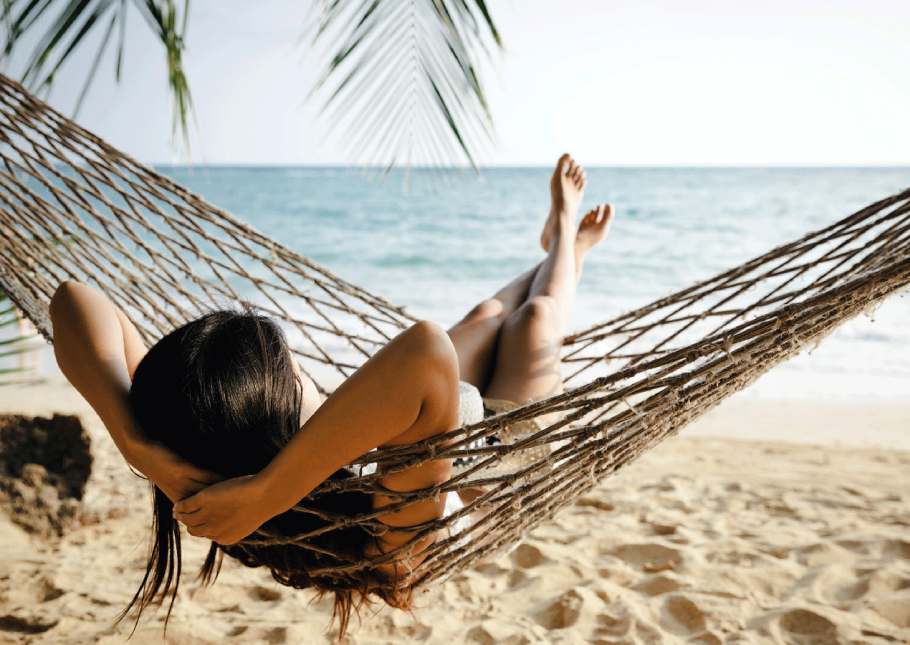 A woman relaxing on a sun lounger on a beautiful beach with crystal clear waters