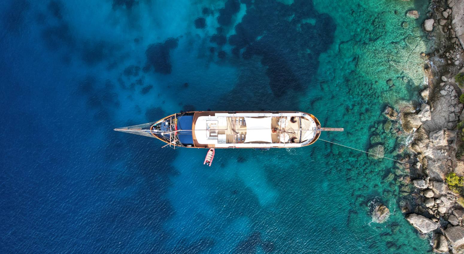 Aerial view of a small cruise ship in a turquoise sea surrounded by islands.