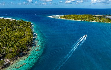 A boat sailing next to two tropical islands