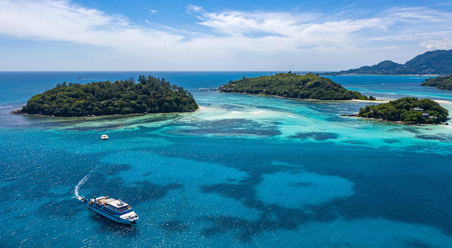 small ship sailing with tropical island on the background