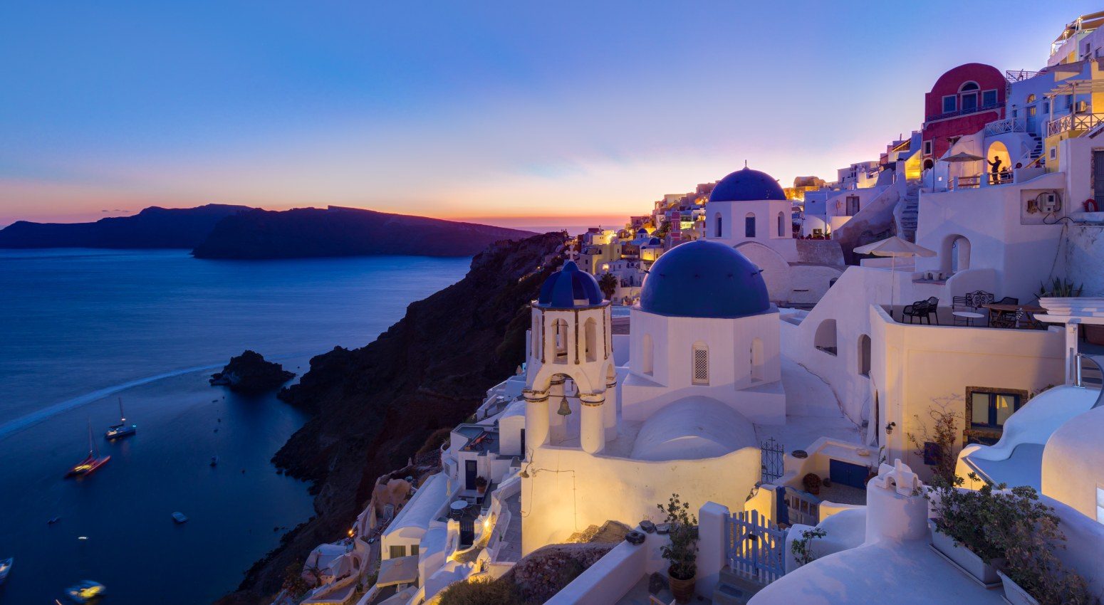 View to traditional white houses in Caldera of Santorini during sunset