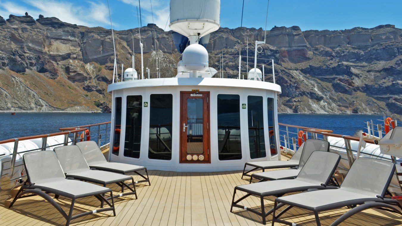 The sun deck on a cruise ship with lounge chairs and a view of the sea