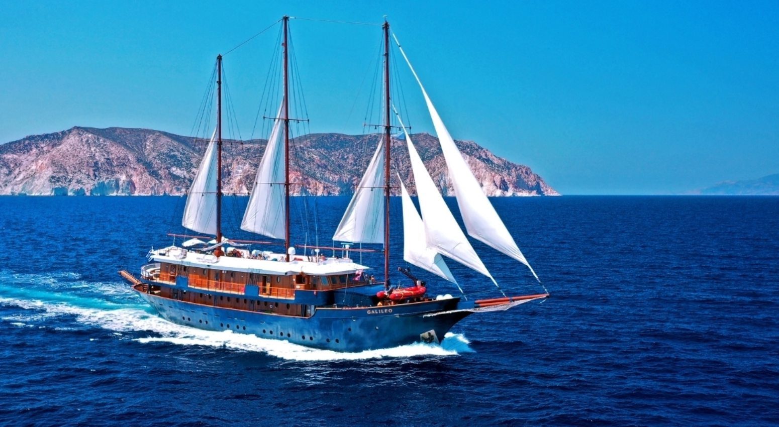 Galileo boat sailing in the ocean with a rocky island in the background