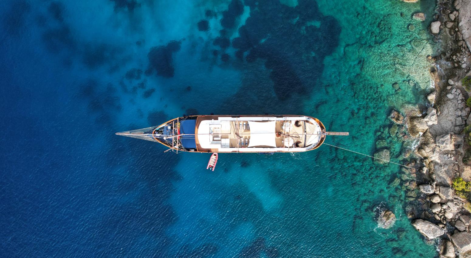Aerial view of a small cruise ship in a turquoise sea surrounded by islands.