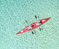 Two people kayaking in turquoise wates in a tropical island