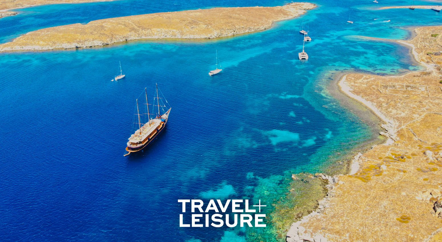 Aerial view of a small cruise ship in a turquoise sea surrounded by islands.