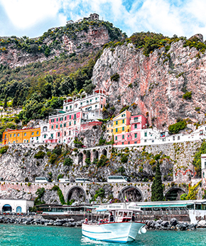 A Variety Cruises ship docked at the Amalfi Coast in Italy, surrounded by cliffs and colorful houses