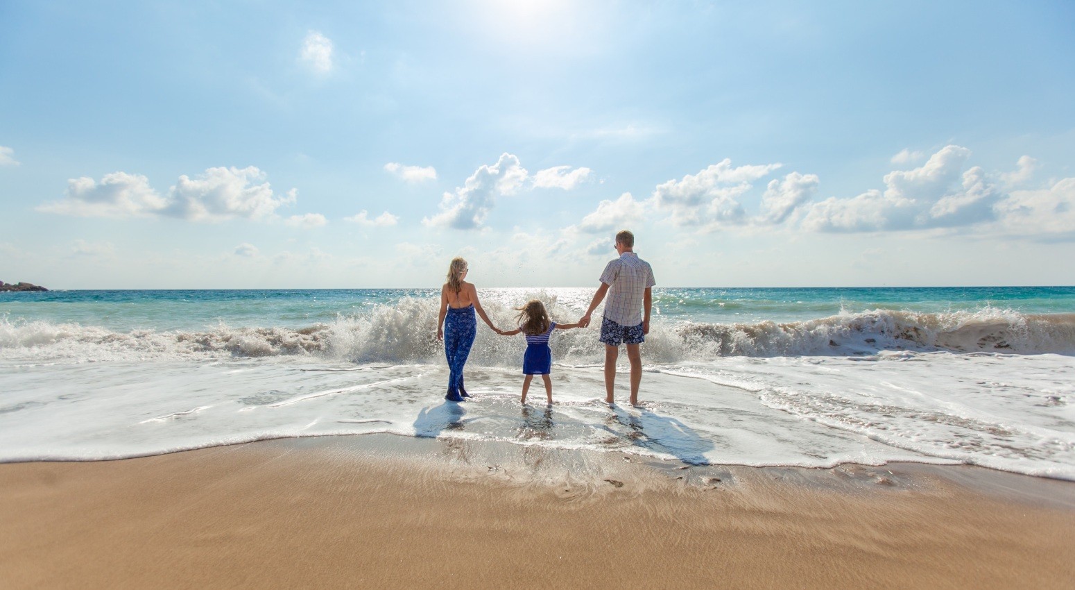 Family enjoying a walk on a sandy beach.