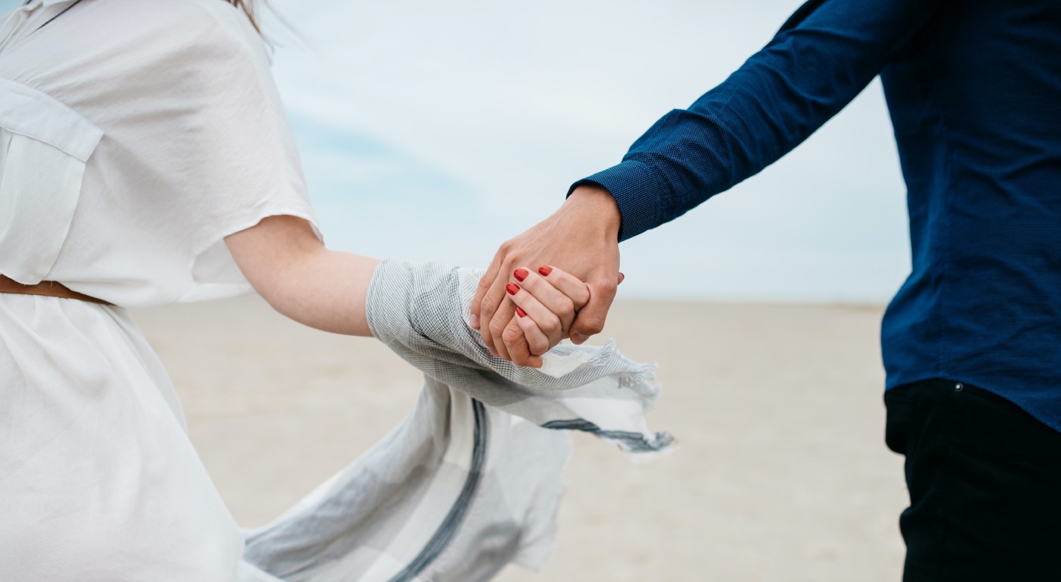 Couple holding hands on the beach.