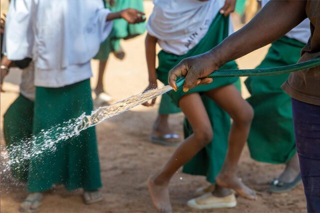 Children playing in the backyard holding a watering hose